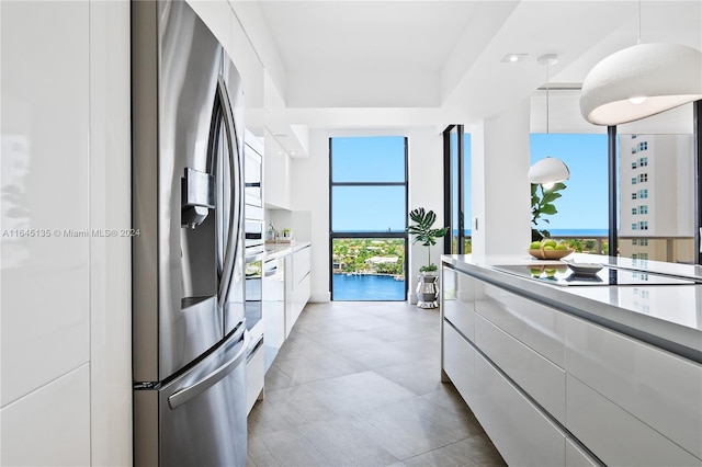 kitchen with white cabinetry, stainless steel fridge, pendant lighting, and light tile patterned floors