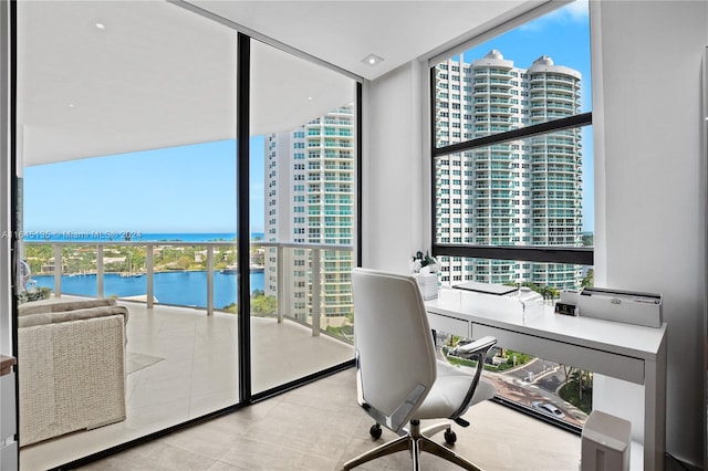 office space featuring plenty of natural light, light tile patterned floors, a wall of windows, and a water view