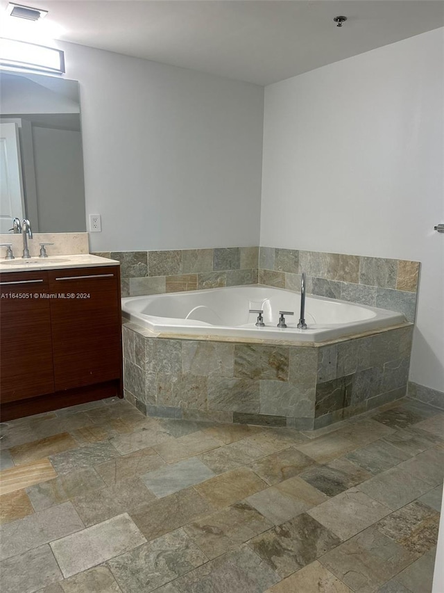 bathroom with tiled tub, vanity, and tile patterned floors