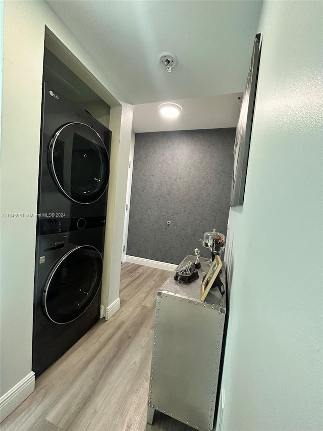 laundry area with light hardwood / wood-style floors and stacked washing maching and dryer