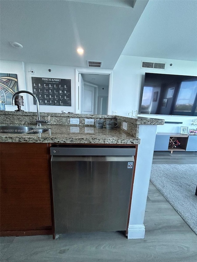 kitchen with sink, stone counters, light hardwood / wood-style floors, and dishwasher