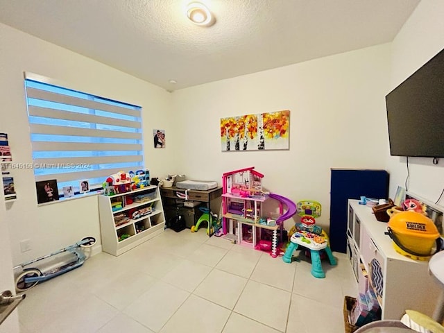 playroom with a textured ceiling and light tile patterned floors