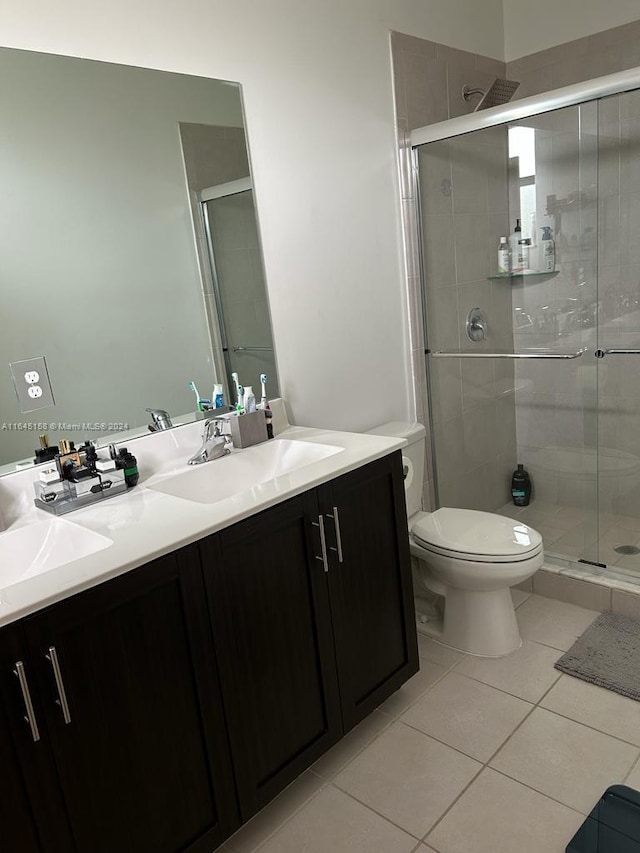 bathroom featuring vanity, a shower with shower door, tile patterned floors, and toilet