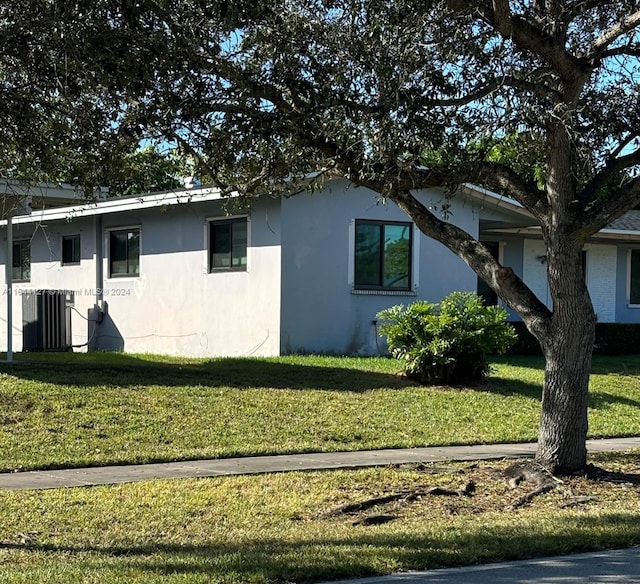 view of property exterior with central AC unit and a yard