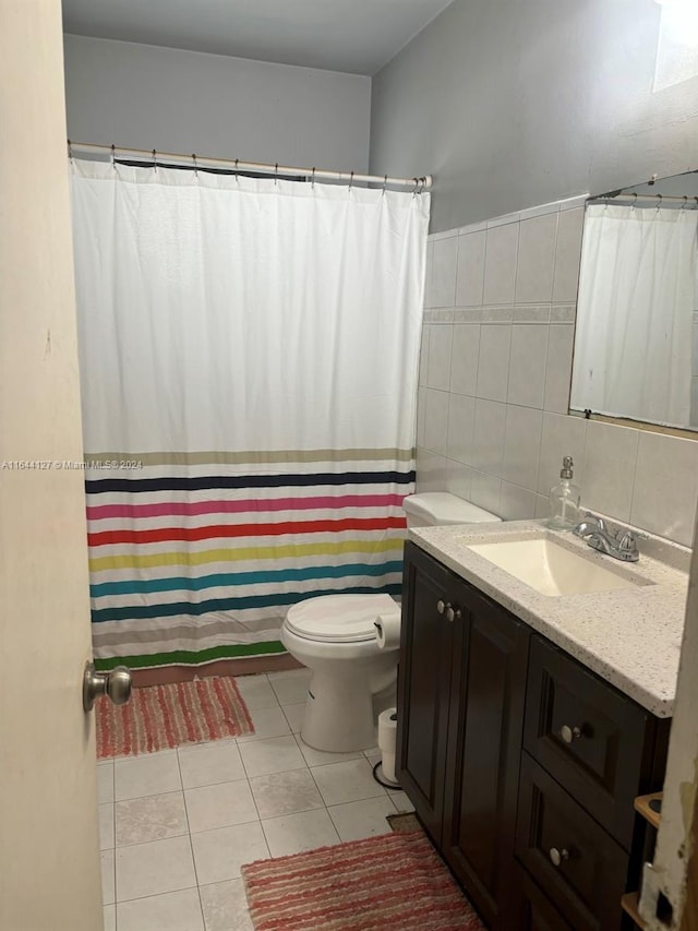 bathroom featuring tile patterned flooring, vanity, toilet, and tile walls