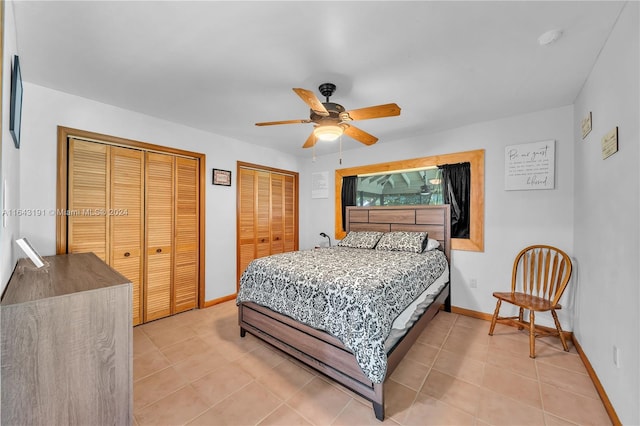 tiled bedroom featuring ceiling fan and two closets