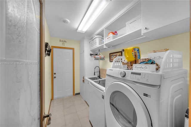 clothes washing area featuring sink, washer and clothes dryer, light tile patterned floors, and cabinets