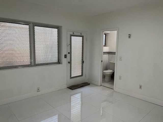 unfurnished bedroom with light tile patterned floors and ensuite bath