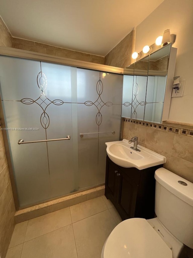 bathroom with tile patterned floors, an enclosed shower, vanity, tile walls, and toilet