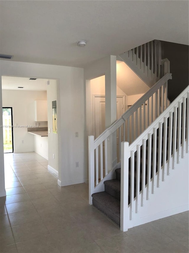 staircase with tile patterned flooring, visible vents, and baseboards