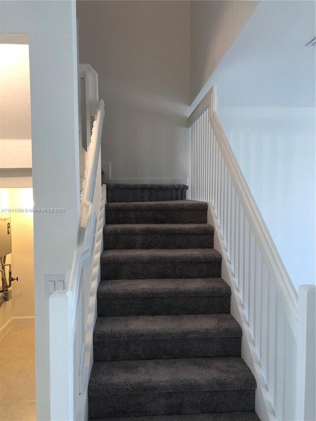 staircase with a towering ceiling and tile patterned flooring