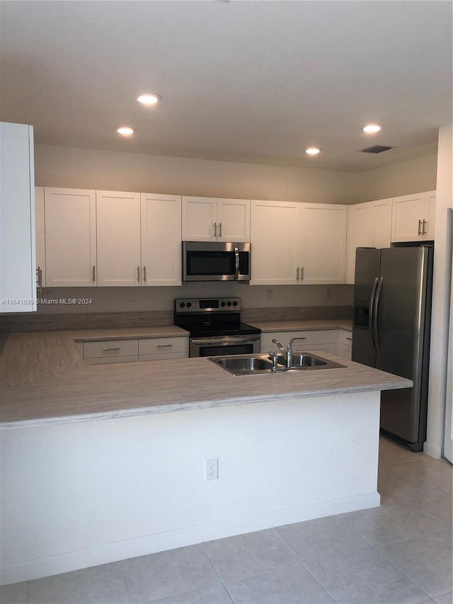 kitchen with sink, stainless steel appliances, light tile patterned flooring, and white cabinets