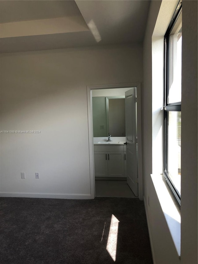 interior space featuring baseboards and dark colored carpet