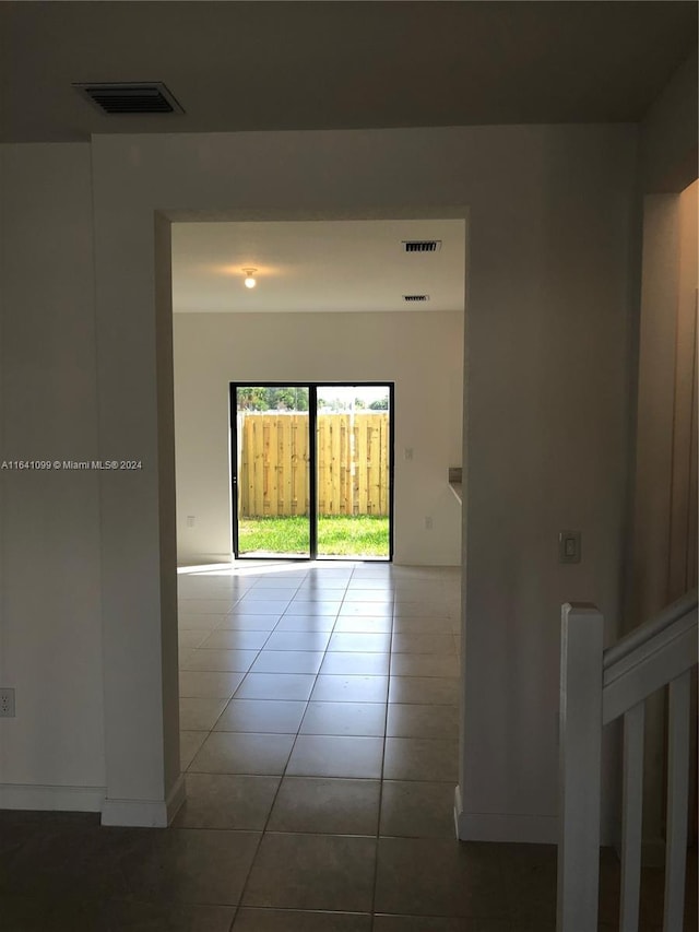 hall featuring baseboards, visible vents, and tile patterned floors