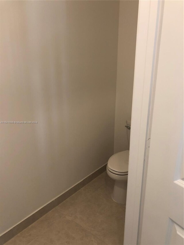 bathroom with toilet, tile patterned flooring, and baseboards