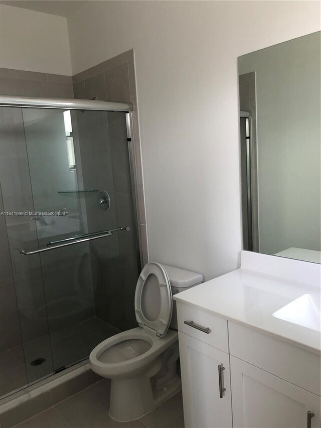 bathroom with tile patterned floors, toilet, an enclosed shower, and vanity