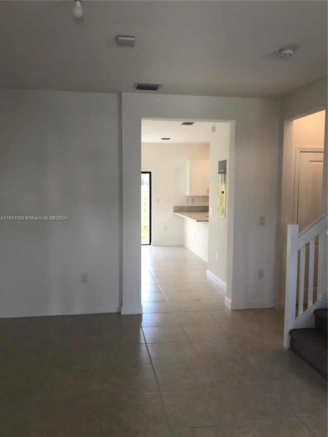 hall featuring stairway, light tile patterned flooring, visible vents, and baseboards