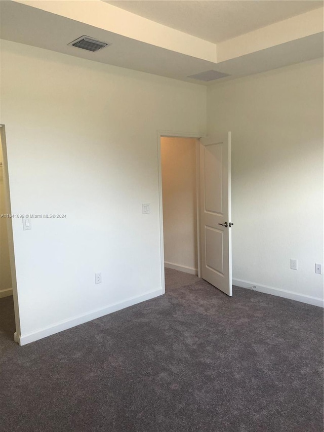 unfurnished room featuring dark colored carpet, visible vents, and baseboards