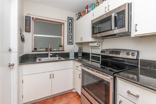 kitchen with sink, dark stone countertops, white cabinetry, appliances with stainless steel finishes, and light tile patterned floors