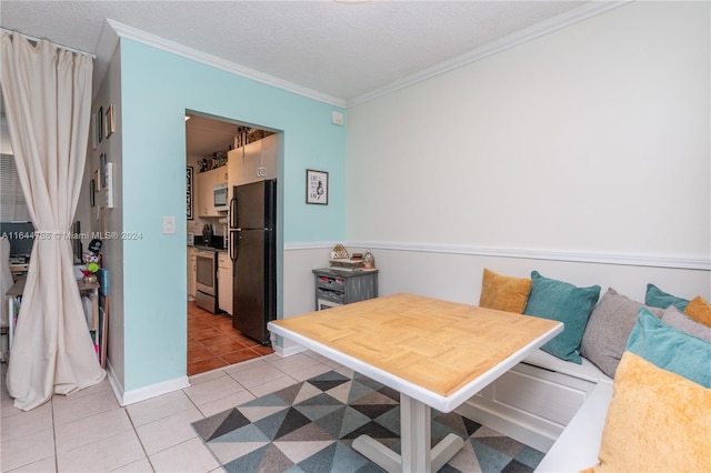 dining space with light tile patterned floors, ornamental molding, and a textured ceiling