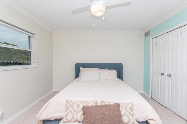 tiled bedroom featuring ceiling fan, a closet, and ornamental molding