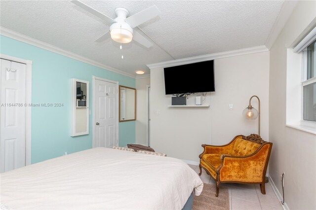 bedroom with a textured ceiling, ceiling fan, ornamental molding, and tile patterned floors