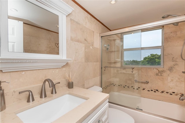 full bathroom with toilet, vanity, ornamental molding, tile walls, and shower / bath combination with glass door