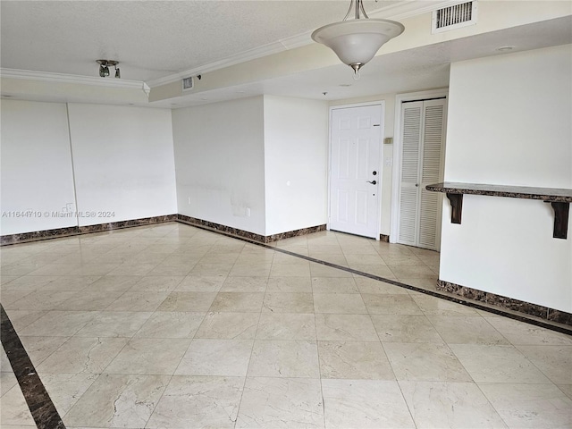 tiled empty room featuring a textured ceiling and ornamental molding