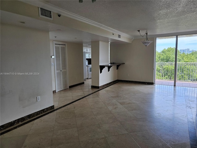 tiled empty room with crown molding, a textured ceiling, and floor to ceiling windows