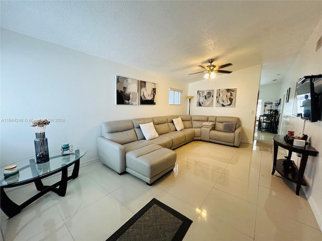 living room with ceiling fan, light tile patterned floors, and a textured ceiling