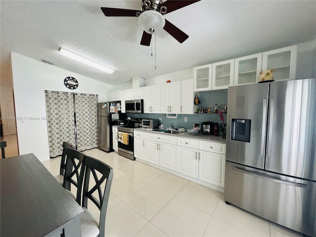 kitchen featuring a textured ceiling, backsplash, stainless steel appliances, and white cabinetry