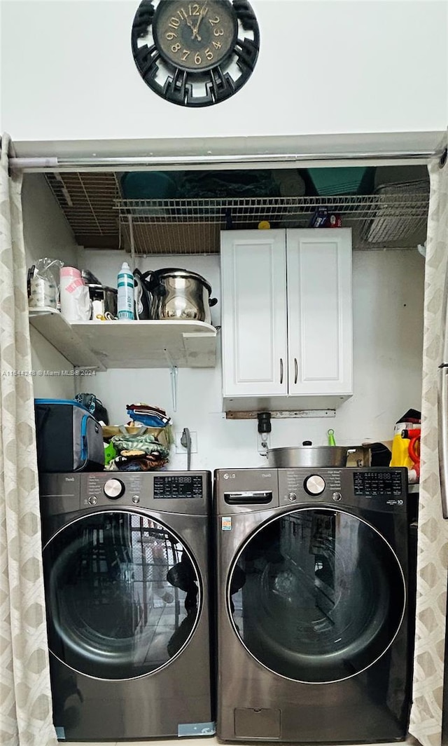 laundry area with washing machine and dryer and cabinets