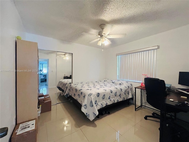 tiled bedroom featuring ceiling fan, a textured ceiling, and a closet