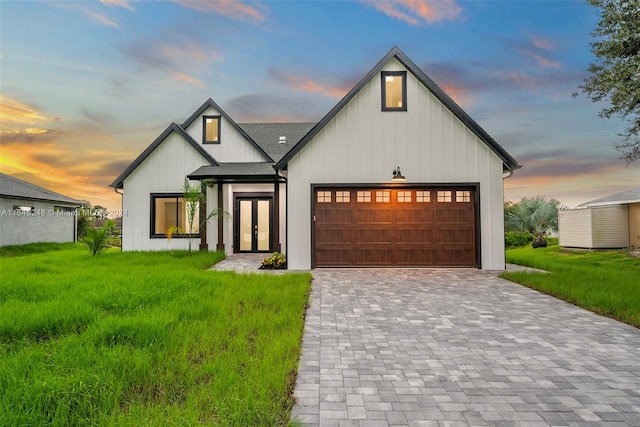 modern inspired farmhouse featuring a garage and a lawn