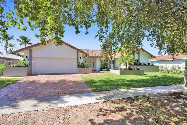 mediterranean / spanish-style home with a garage and a front lawn