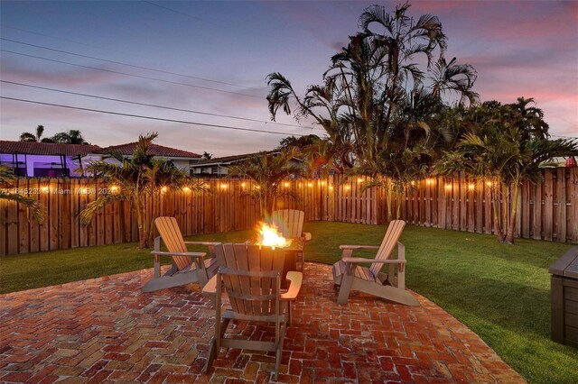 patio terrace at dusk with a fire pit and a yard