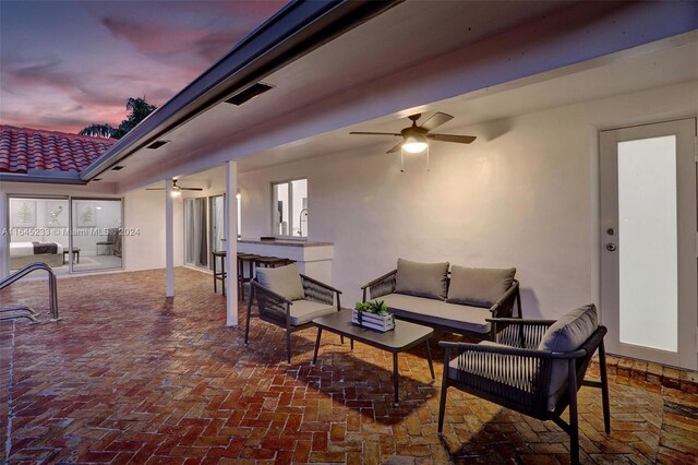 patio terrace at dusk featuring ceiling fan and outdoor lounge area