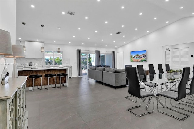 dining space featuring high vaulted ceiling and light tile patterned floors