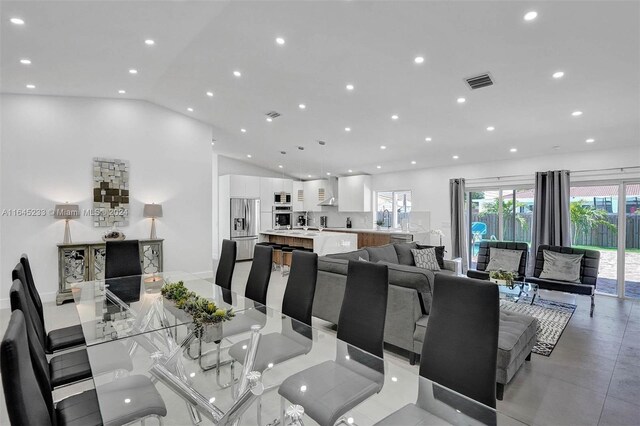 dining area with vaulted ceiling and light tile patterned floors