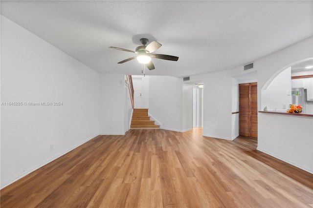 unfurnished living room featuring a textured ceiling, light wood-type flooring, and ceiling fan