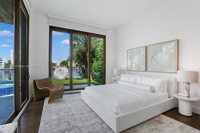 bedroom featuring dark hardwood / wood-style flooring, access to outside, and a water view