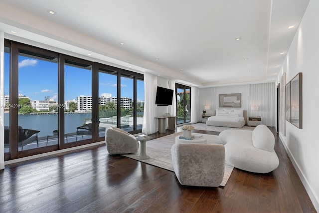 bedroom with access to exterior, a water view, floor to ceiling windows, and hardwood / wood-style flooring