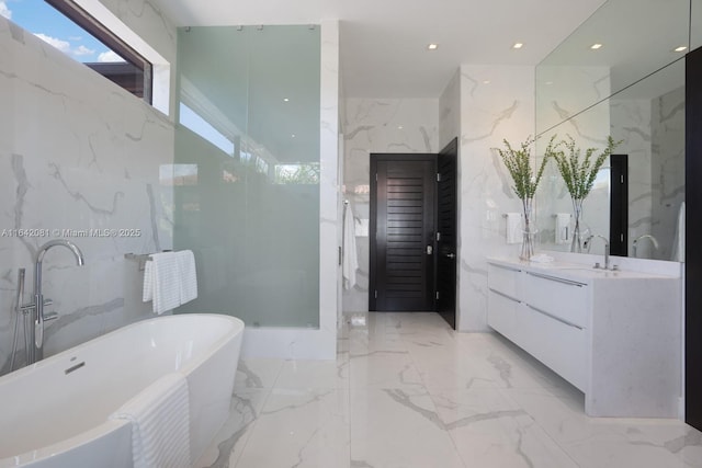 bathroom featuring a tub to relax in, vanity, and tile walls