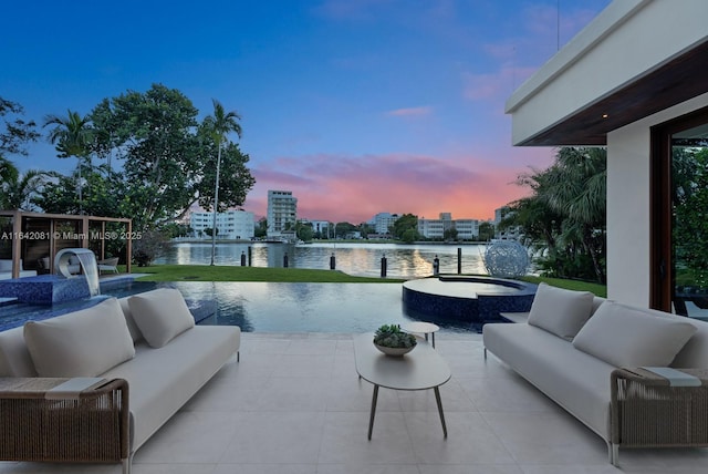 pool at dusk with outdoor lounge area, a patio area, a water view, and an in ground hot tub