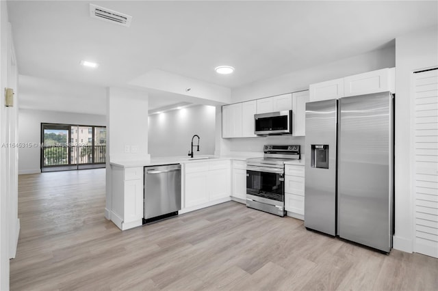 kitchen with sink, stainless steel appliances, white cabinets, and light hardwood / wood-style flooring