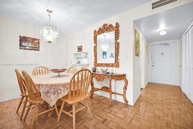 dining room featuring a textured ceiling, light parquet flooring, and a chandelier