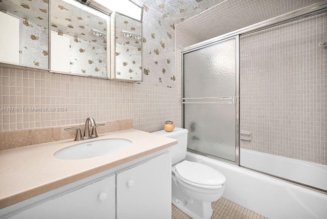 full bathroom featuring combined bath / shower with glass door, vanity, tile patterned floors, and tile walls