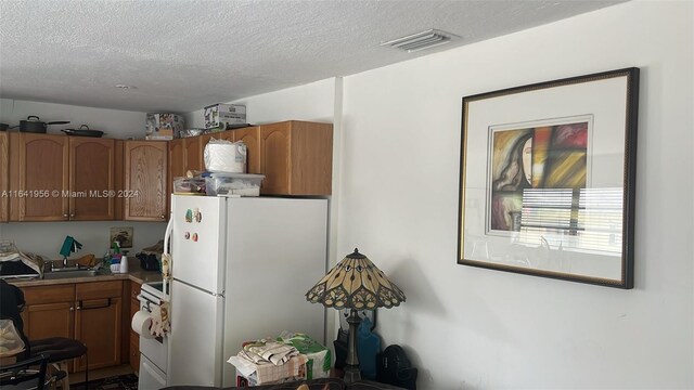 kitchen with a textured ceiling and white appliances