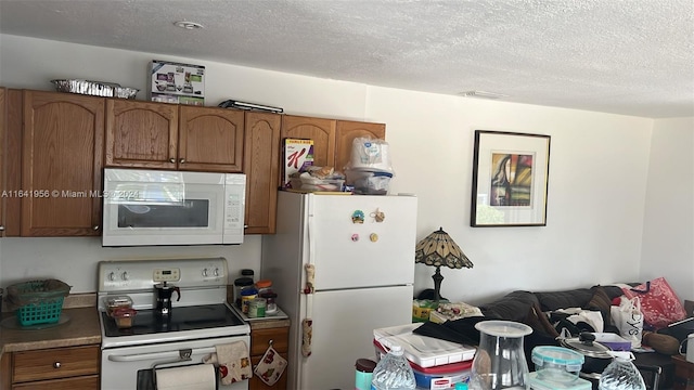 kitchen featuring a textured ceiling and white appliances