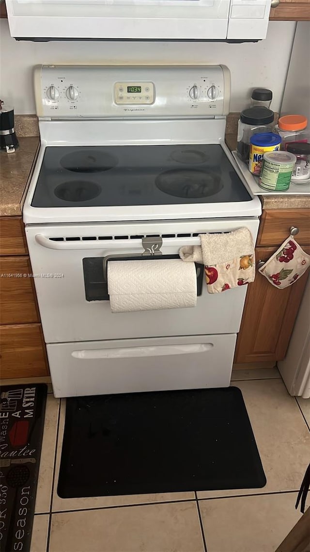 interior details with white range with electric cooktop and light tile patterned floors